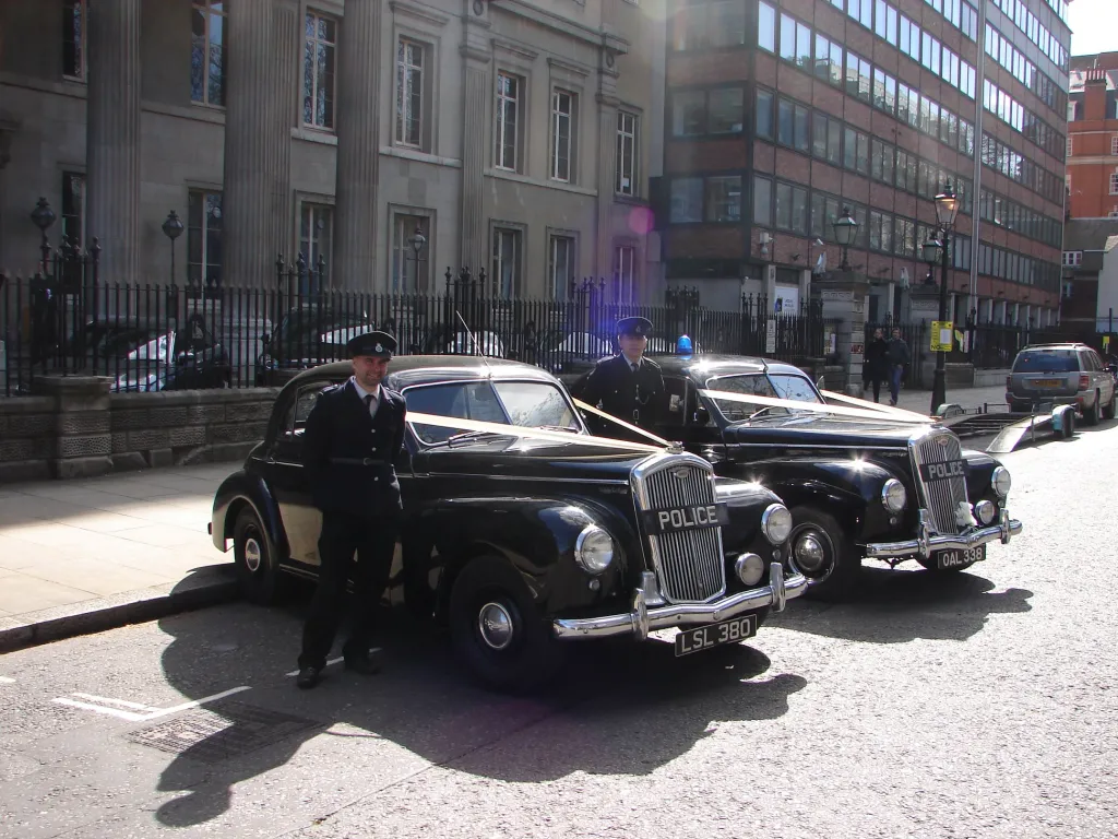 Two Black Classic Wolseley wedding cars with police sign and their chauffeurs wearing period police uniform