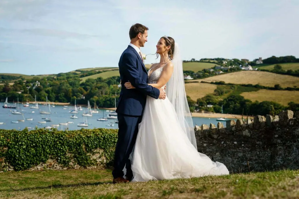 Bride and GRoom kissing on the ground of the Salcombe Hotel with view of the sea in the background
