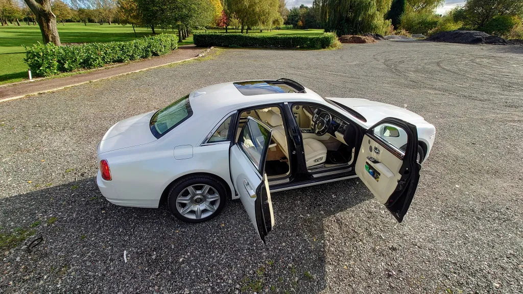 White rolls-royce ghost with doors open showing Cream leather interior
