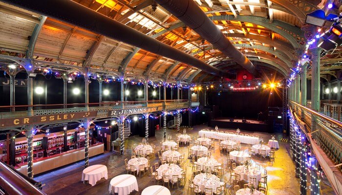 a brightly lit hall with wedding tables set up and original grocers signs above the bar area