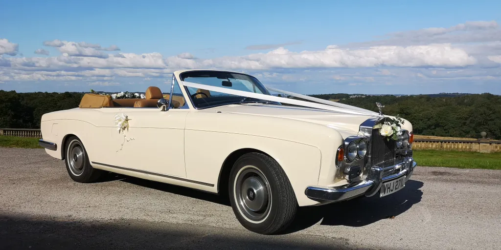 Ivory Classic Rolls-Royce Corniche with ivory ribbons and a sky blue background