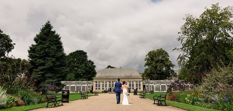 Bride and Groom walking holding arms towards the botanic gardens