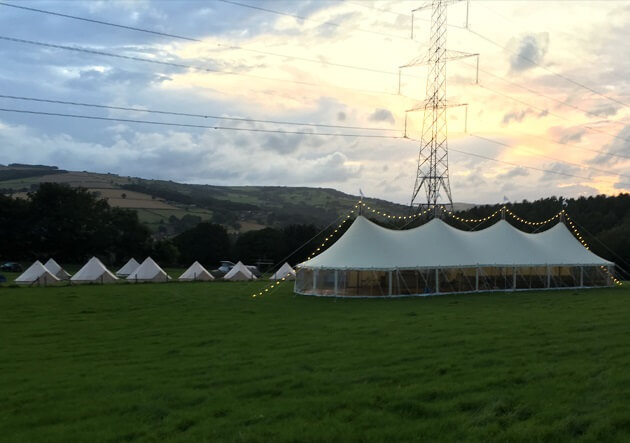 White Marquee on green field decorated with fairy lights