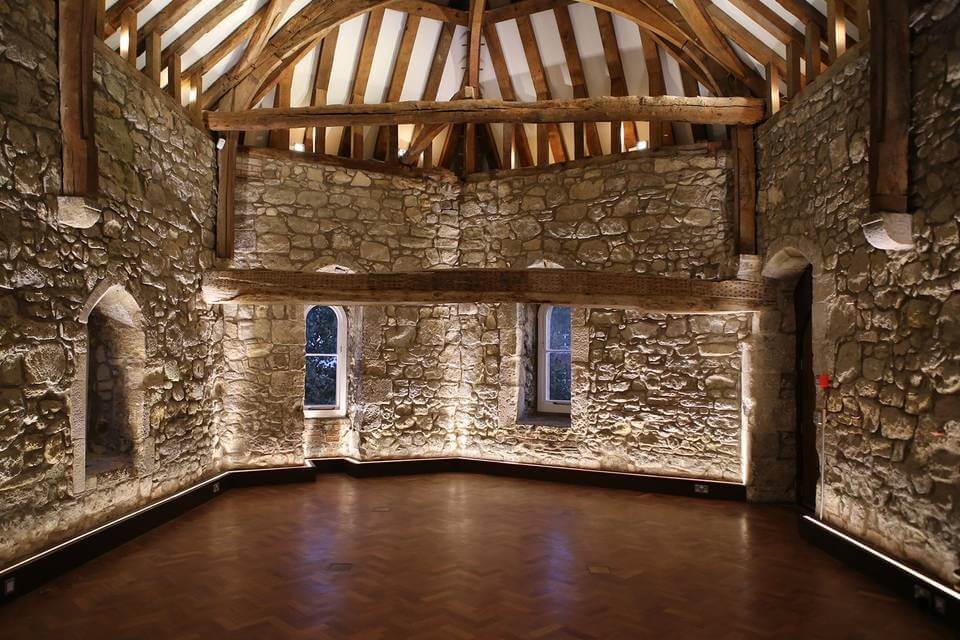 Empty room with dark wooden floor, light wooden ceiling beams and brick wall