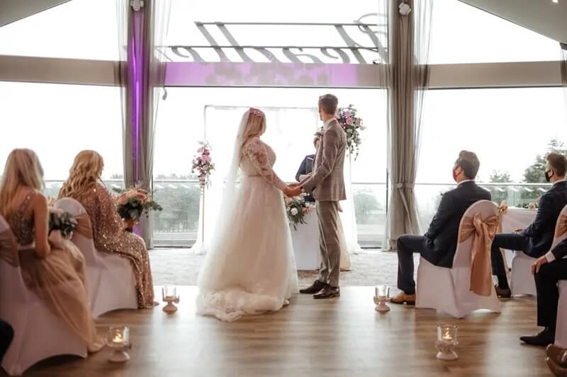 Bride and Groom Holding hands in the cermeony room in front of the Registrar