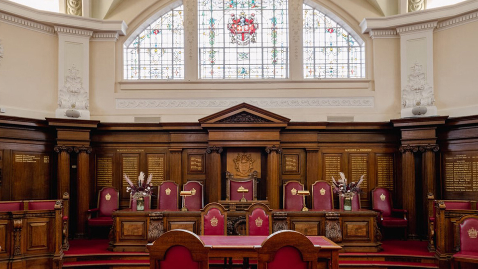 Ceremony Room at islington Town hall with carved wooden walls, designer glass windows, wooden table and chairs with Burgundy covers