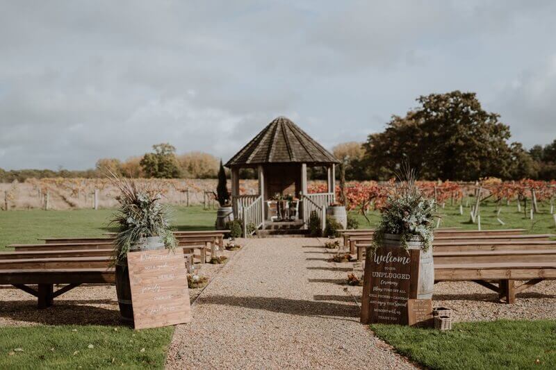 Outdoor area with wooden bench seats for guests to seat while couple gets married under the wooden arch