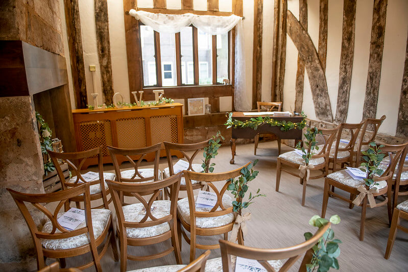 Ceremony Room with Wooden chairs decorated with green foliage, wooden beams on the walls