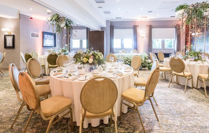 Wedding Reception Room with white cloth and white flower decoration in the middle of the round tables