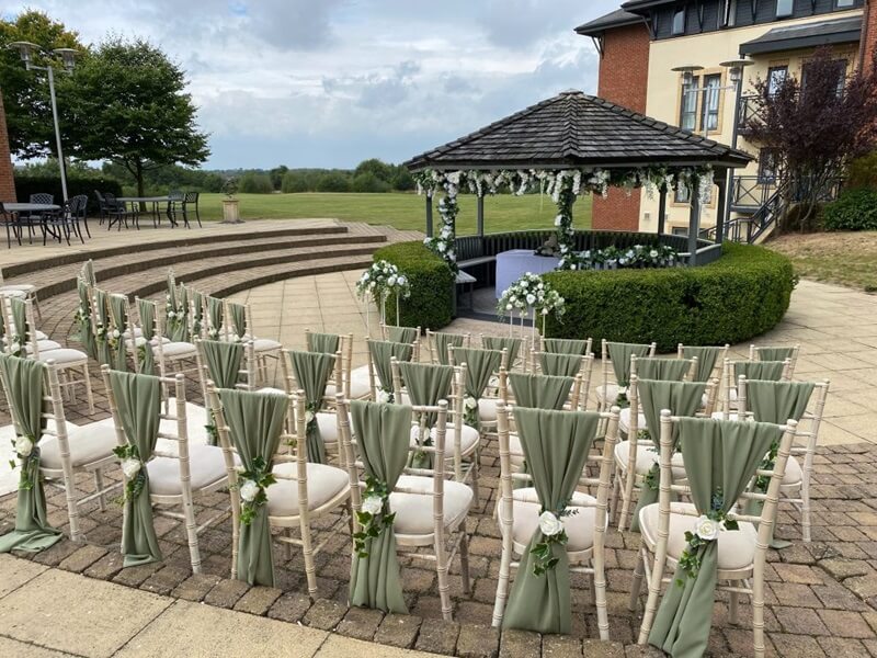 outdoor Ceremony with chairs decorated with Sage Green sashes