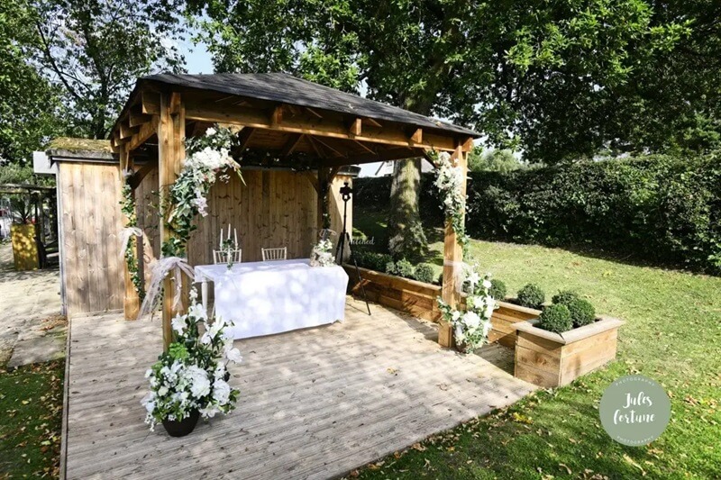 Outdoor wedding ceremony made of wood and decorated with large white wedding bouquet