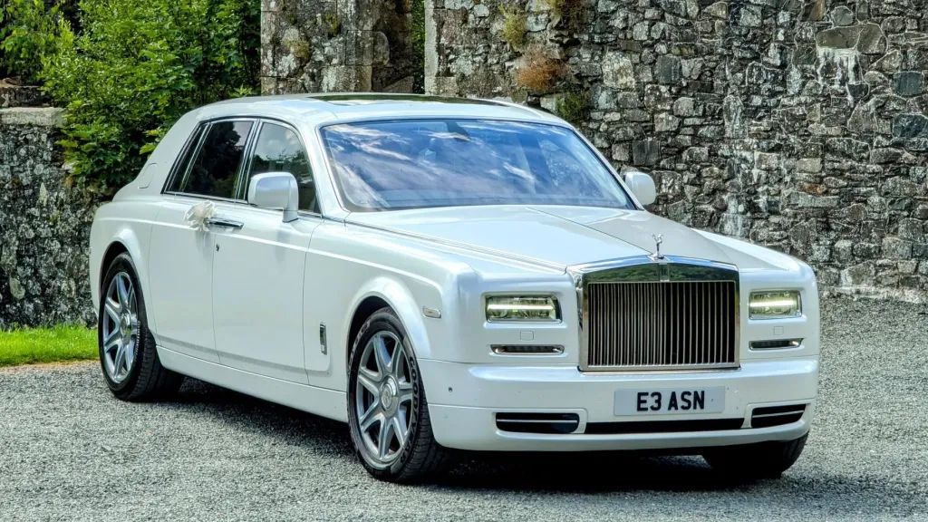 White Rolls-Royce Phantom parked in front of a brick wall