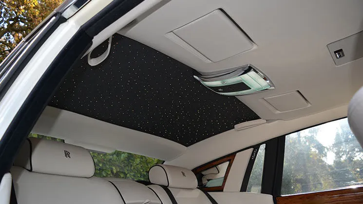 Photo taken from outside the vehicle with the door open aiming at the ceiling showing the starlight roof lit up inside Rolls-Royce phantom