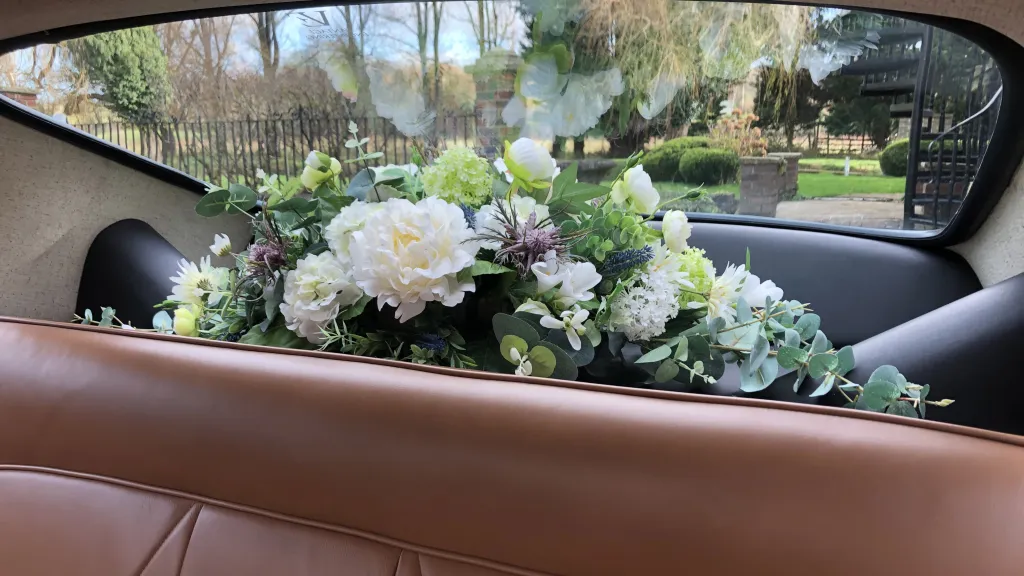 Silk flower arrangement on the rear parcel shelf of a wedding car