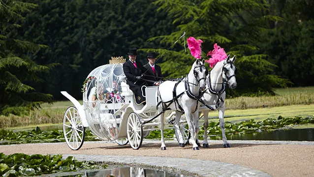 A glass cinderella carriage pulled by two white horses and their coachmen