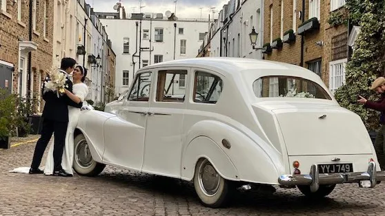 Rear view of classic 7-saeater Austin Princess Limousine with Bride and Groom parked in street of London by the Old Marylebone Town Hall
