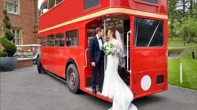 Vintage Red double decker routemaster bus with Bride and Groom posing for photos by the rear Open Platform after their Chealsea Town Old Wedding ceremony