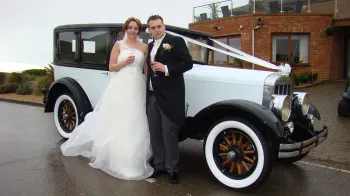 Bride and Groom standing in front of the Vintage Franklin posing for their wedding photographer