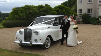 Bride and Groom stnasing next to the Austin Princess Limousine