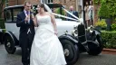 Bride and Groom with a white vintage Citroen Deluxe Saloon in the background dressed with wedding ribbons