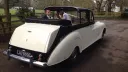 Bride and Groom sat in the rear of an Austin Princess Landaulette with roof open looking at each others
