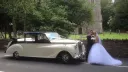 Bride and groom standing in front of an Austin Princess Limousine in Black and Ivory in front of a church in Leicester