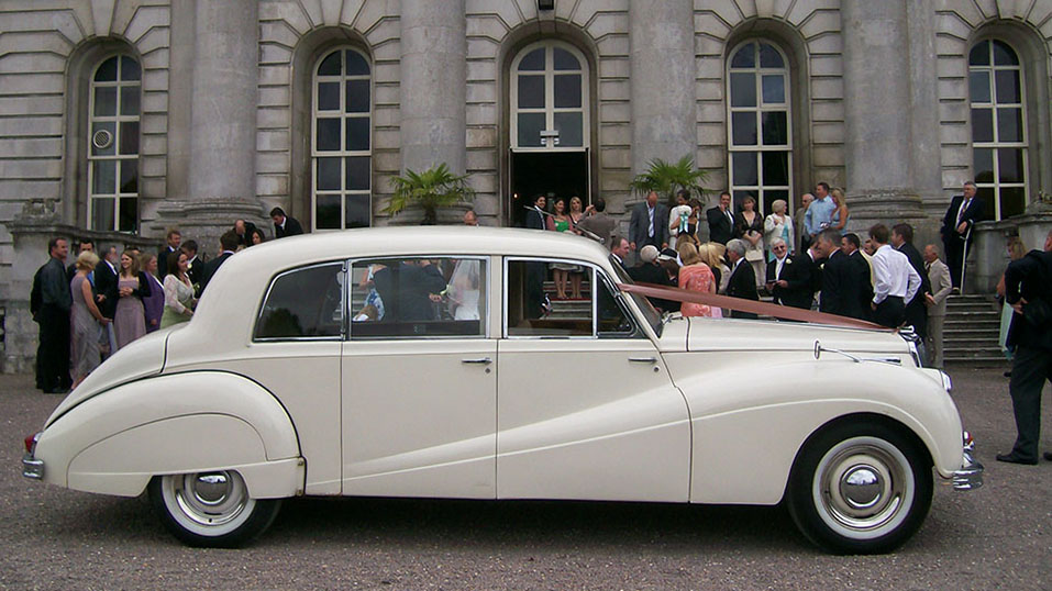 wedding guests having photos taken in front of the wedding venue in Uxbridge with the classic car
