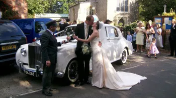 Classic White Rolls-Royce with couple and their wedding chauffeur on the day of their wedding
