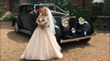 Bride and Grom kissing in front of vintage Rolls-Royce Phantom II Continental LWB
