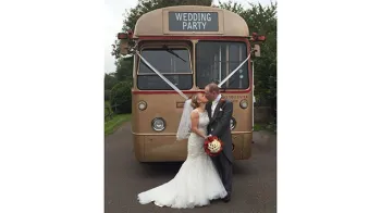 Bride and Groom kissing in front of Gold Single Decker Bus