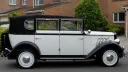 right side view of white regent with black soft top roof close. White wheels with chrome centre caps