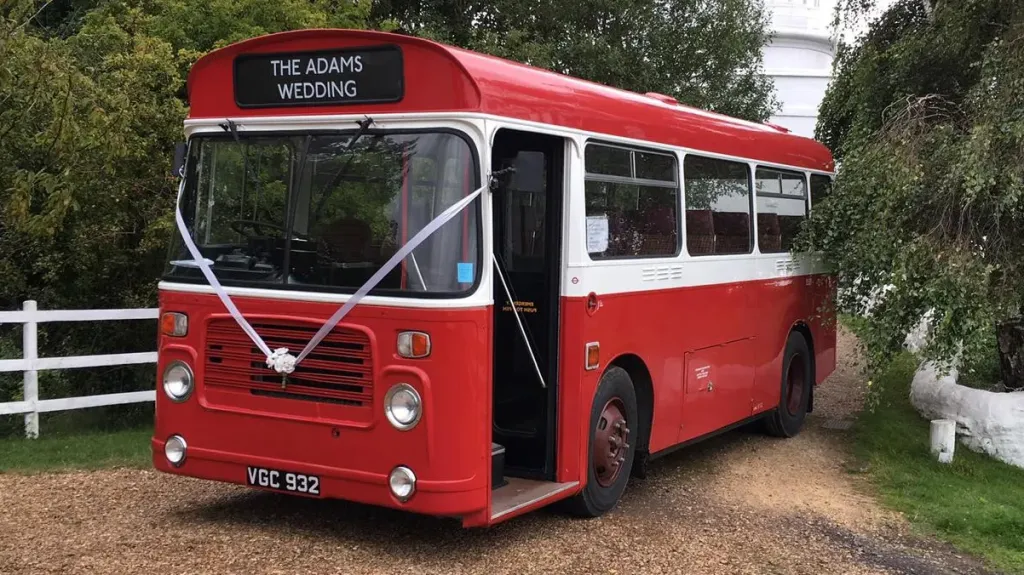 Left side view of White and Red classic single decker with front passenger door open and decorated with white ribbons and bow at the front