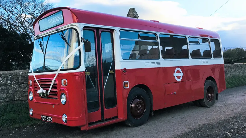 Left side view of a white and red classic Single decker bus with front doors closed