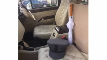 Front passenger cream leather seat inside Taxi Cab with white umbrella and a grey chauffeur's hat on the seat