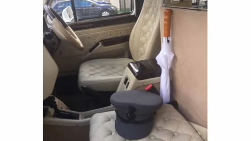 Front passenger cream leather seat inside Taxi Cab with white umbrella and a grey chauffeur's hat on the seat