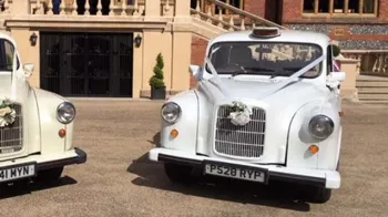 Front view of a classic white taxi cab dressed with white ribbons and bows on the front grill