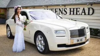 Rolls-Royce Ghost with Bride wearing a white dress standing by the vehicle