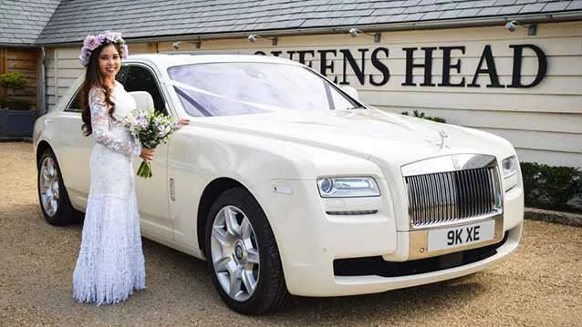 Rolls-Royce Ghost with Bride wearing a white dress standing by the vehicle