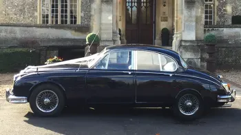 Left side view of Daimler 250 V8 parked in front of a chruch