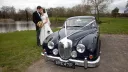 Bride and Groom kissing standing by classic Daimler