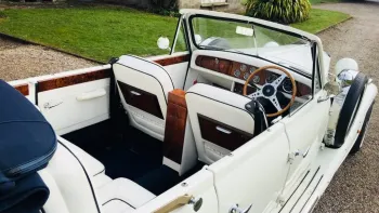 Aerial photo take of a vintage Beauford in White with hood open showing the white leather interior and wooden dashboard