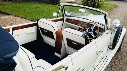 Aerial photo take of a vintage Beauford in White with hood open showing the white leather interior and wooden dashboard