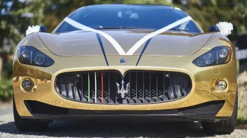 Full Front view of Maserati GranTurismo decorated with White ribbons and Trident logo in the middle of the grill