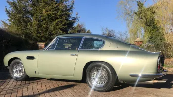 Rear left view of Aston Martin DB6 in pale metallic green and shiny chrome spokes wheels