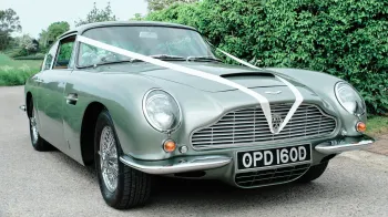 Front view of Aston Martin DB6 in pale metallic green decorated with white ribbons