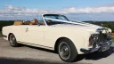 Rolls-Royce Corniche Convertible decorated with white ribbons and roof  open with a bright blue sky in the background