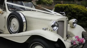 Front bonnet view of Ivory Beauford convertible with ribbons and white and pink flowers on front bumper.