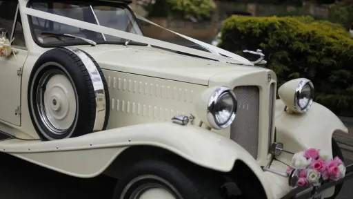 Front bonnet view of Ivory Beauford convertible with ribbons and white and pink flowers on front bumper.