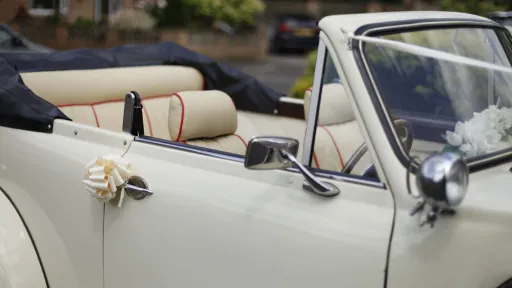 Black soft-top roof open on Ivory Beauford showing cream leather interior. Ivory bow on the door handle