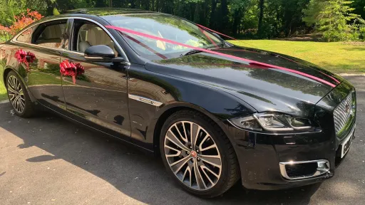 Front Rigjht view of a Jagaur XJ in Black with Red WeddingBows on Door Handles.